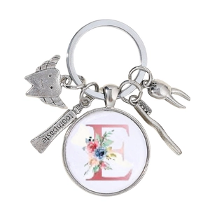 Détail du porte-clés dentiste avec brosse à dents, tube de dentifrice et lettre florale E