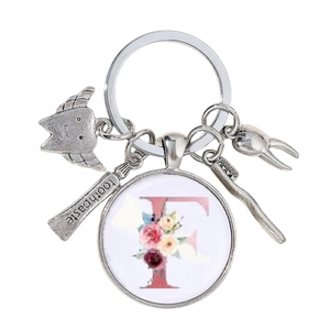 Détail du porte-clés dentaire créatif avec lettre F fleurie et petits charms
