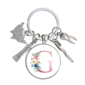Porte-clés dentaire détaillé avec breloques argentées et pendentif lettre G fleurie