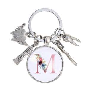 Détail du porte-clés dentiste avec lettre M fleurie, fée des dents et dentifrice