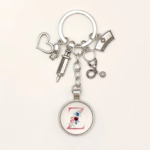 Detail of medical keychain with syringe, heart and letter Z pendant on white background