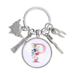 Détail de breloques dent avec brosse à dents et lettre P fleurie sur porte-clés