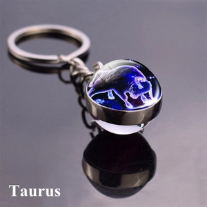 Macro shot of Taurus zodiac double-sided glass ball keychain with luminous blue star pattern
