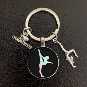 Close-up of gymnastics keychain with silver charms and colorful silhouette on leather