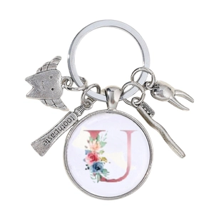 Détail d'un porte-clés dentaire avec dent en argent, brosse à dents et lettre U fleurie