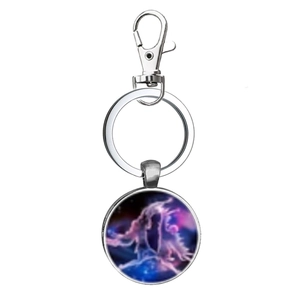 Detail of metal Gemini constellation keychain featuring a celestial star art glass dome