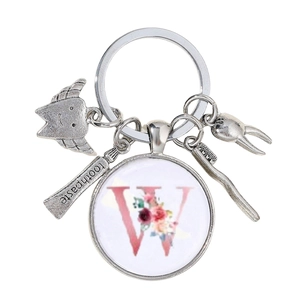 Détail du porte-clés dentaire avec breloques de dents et pendentif fleuri lettre W