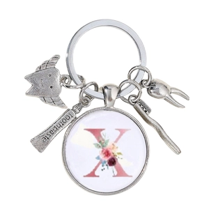 Détail de porte-clés dentiste avec breloques dent, dentifrice et pendentif fleur lettre X