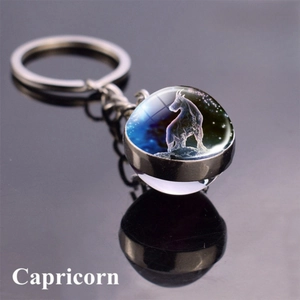 Close-up of a double-sided glass orb keychain featuring the Capricorn constellation