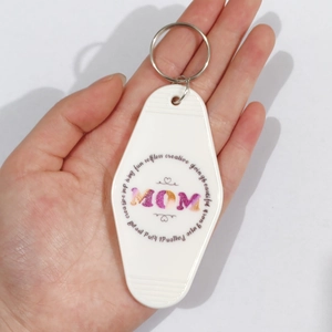 Hand holding a vintage white motel keychain with MOM glitter text for Mother's Day