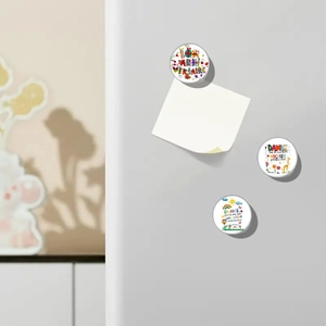 Close-up of circular glass magnets with birthday illustrations on a fridge panel