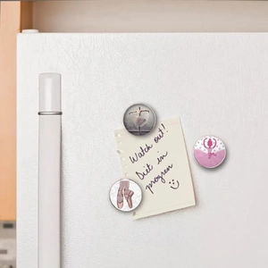 Three ballet-themed 25mm glass magnets holding a handwritten note on a white fridge door