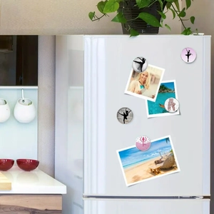 Detail of ballet dancer silhouette glass magnets holding photos on a fridge surface