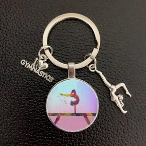 Gymnastics keychain detail featuring heart charm and colorful gymnast silhouette pendant