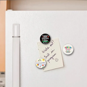 Close-up of 25mm round glass magnets with German Schulkind and Spanish quote designs