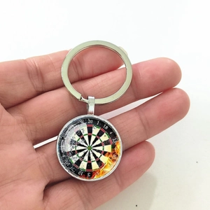 Close-up of dartboard keychain with fire and ice design held in hand for scale