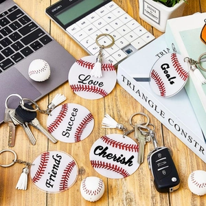 Flat lay of acrylic baseball keychains with white tassels and motivational words on wood