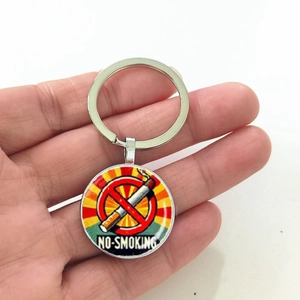 Close-up of a metal no-smoking sign keychain with a red and yellow radial background
