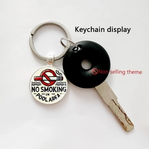 Close-up of circular no smoking in pool area keychain with metallic frame and wood texture