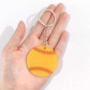 Primo piano di un portachiavi da baseball in acrilico giallo tenuto in mano per le dimensioni