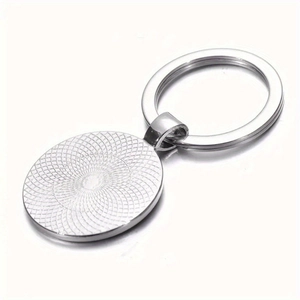 Detailed view of silver metal keychain featuring sunburst texture and oval pendant