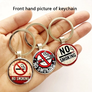 Detailed view of three circular metal keychains with No Smoking signs on a wooden texture