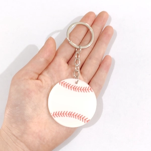 Dettaglio di un portachiavi da baseball bianco con cuciture rosse e anello in metallo