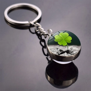 Macro shot of glass ball pendant with green clover pattern on reflective surface