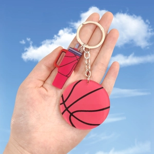 Détail de breloques basket-ball en acrylique et gourde rouge sur un porte-clés en métal