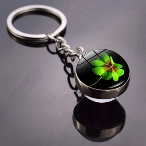 Close-up of a double-sided glass ball lucky four-leaf clover keychain with silver metal ring