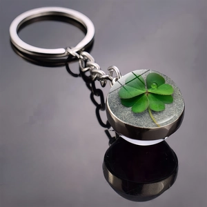 Detailed close-up of a silver keychain featuring a real green four-leaf clover in a glass orb