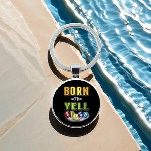 Close-up of metal keychain with Born to Yell Bingo text over blue water background