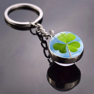 Close-up of a silver four-leaf clover keychain with a crystal glass ball pendant