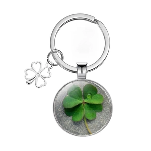 Close-up of four-leaf clover keychain with green glass pendant and silver charms