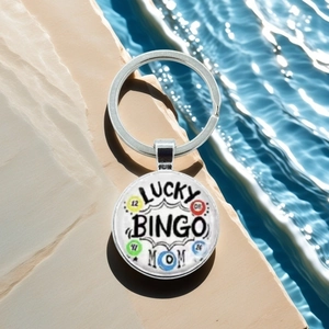 Close-up of metal keychain with Lucky Bingo Mom design on a stone surface with water ripples