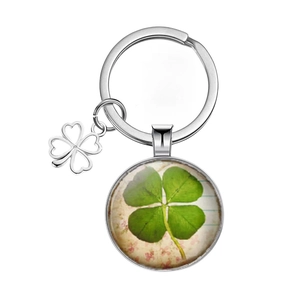 Detailed close-up of a silver four leaf clover keychain with a retro glass floral pendant