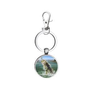 Porte-clés en métal argenté avec pendentif rond illustrant un bar sautant hors de l'eau