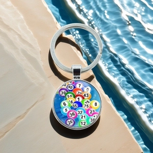 Detail of round metal keychain with colorful bingo ball numbers on blue water background