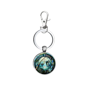 Détail d'un porte-clés de pêche argenté avec motif Gone Fishing sous dôme en verre