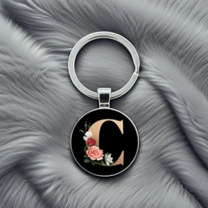 Macro detail of silver metal keychain featuring a gold letter C with floral patterns