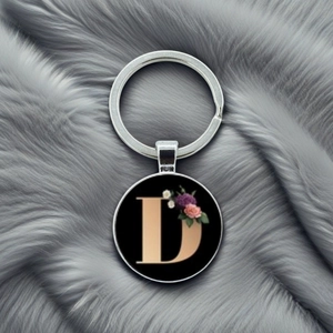 Detailed macro of silver keychain with floral letter D on black glass pendant