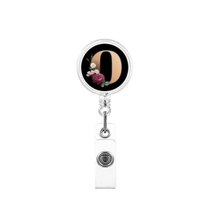 Detail view of retractable badge holder with floral letter O on a black background