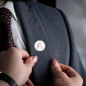 Close-up of a floral letter A brooch badge pinned on a gray striped suit lapel
