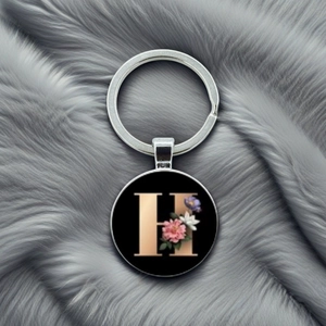 Close-up of letter H keychain with floral design on a soft textured grey background