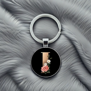 Detail of metal keychain featuring letter L with pink roses and daisies on black background