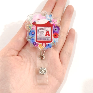 Detail of retractable badge reel featuring A-type blood bag and floral acrylic design