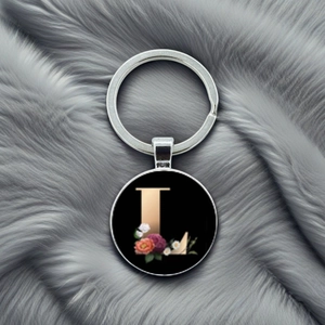 Macro detail of silver keychain featuring a black glass dome with a gold letter L and flowers
