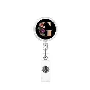 Detail of retractable badge reel featuring a golden letter G and rose floral design