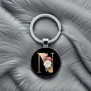 Detailed view of metal keychain with letter N and floral design on grey fur background