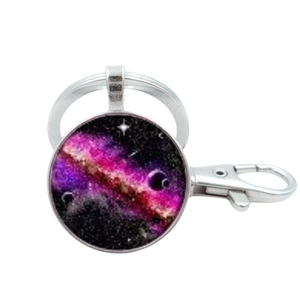 Detail of galaxy-themed glass dome keychain with purple nebula pattern and silver frame